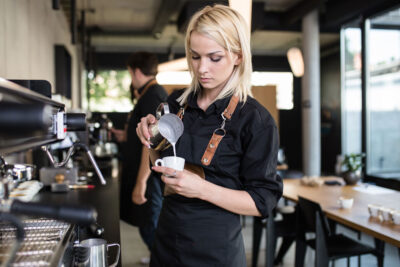 Baristka nalévá našlehané mléko do šálku